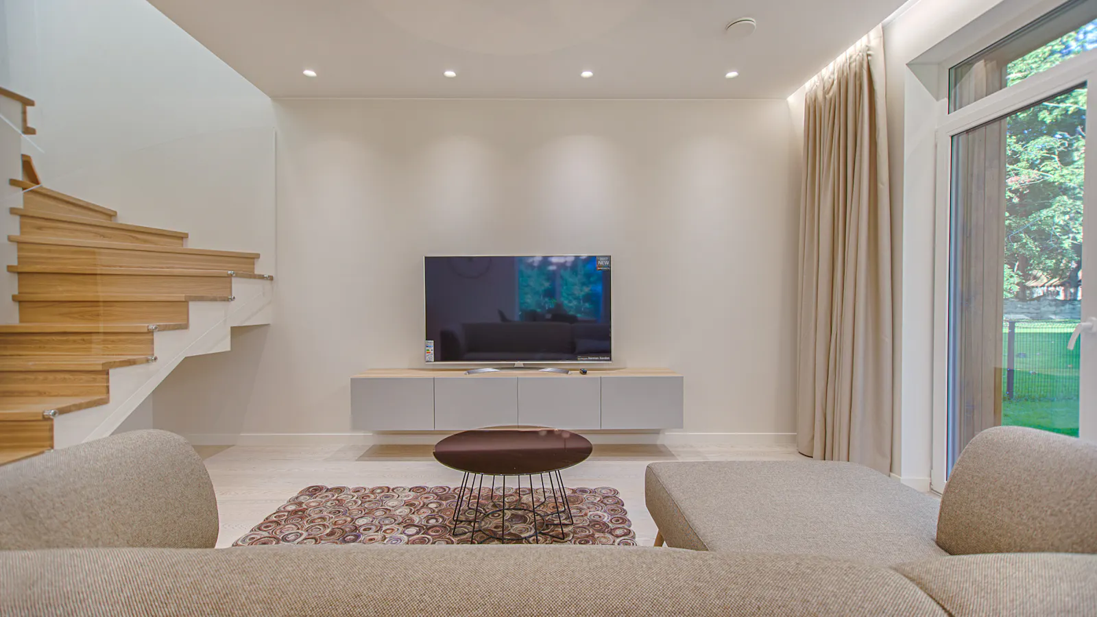 Ein Sofa mit Blick auf einen großen Fernseher in einem modernen Wohnzimmer
